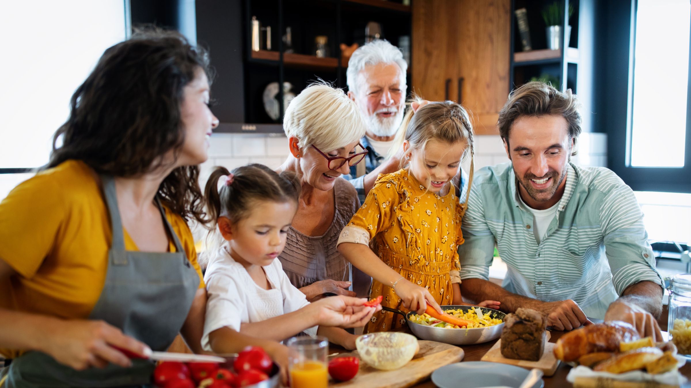Grosseltern mit Kindern und Enkelkindern in der Küche bei der Essenszubereitung